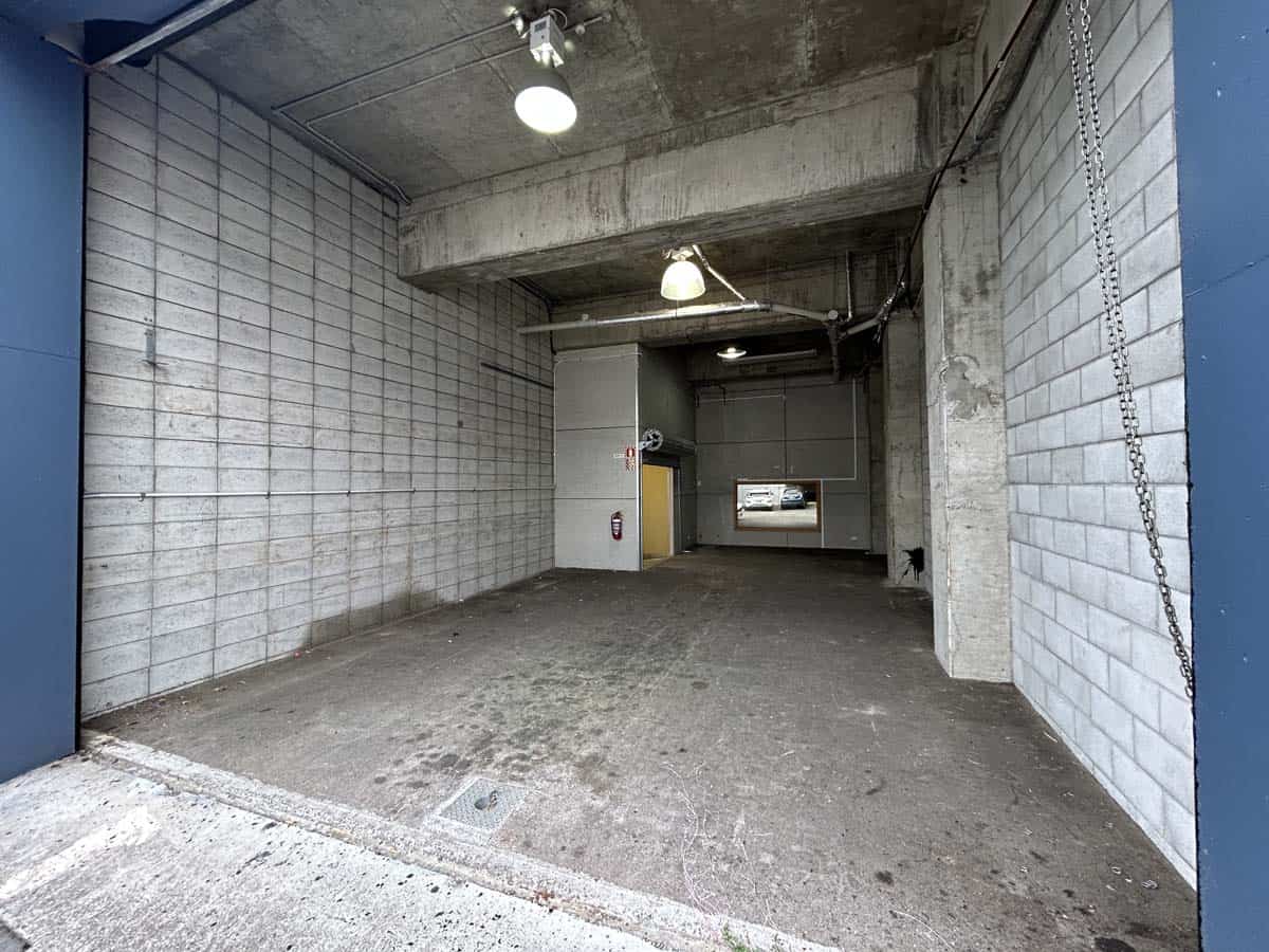 Empty parking garage with concrete walls and ceiling, industrial lighting.