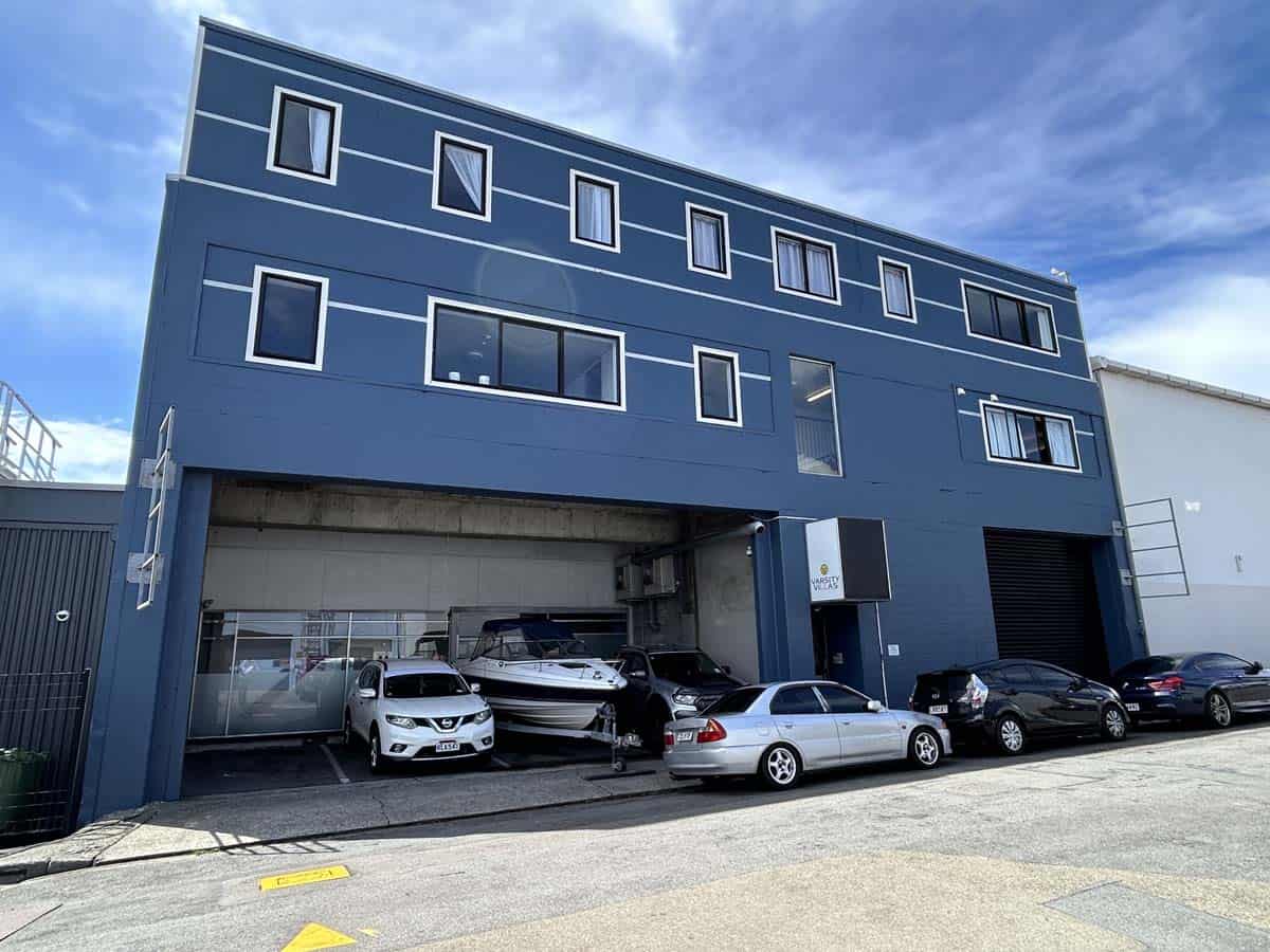 Contemporary blue office building with large windows and parking area.