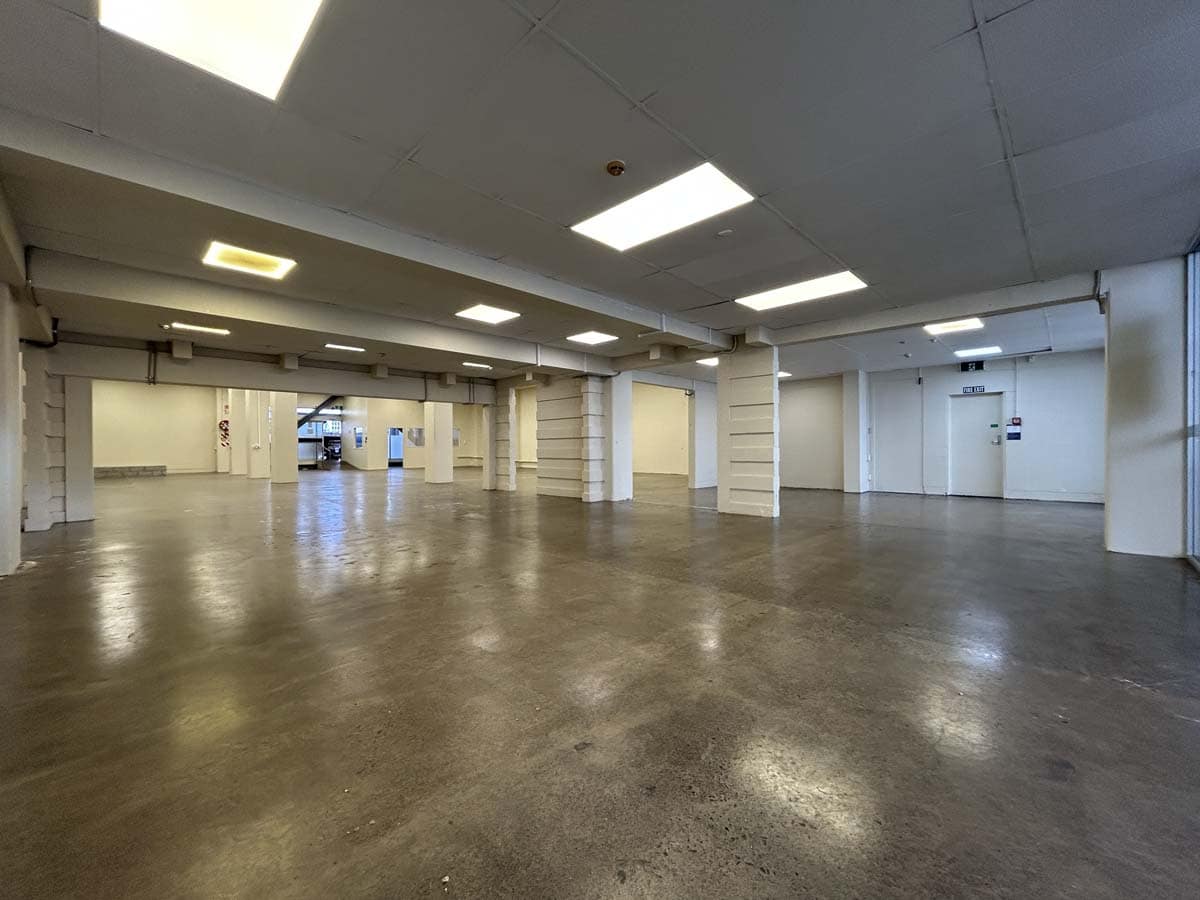 Spacious, empty indoor parking garage with concrete floors and ceiling lights.