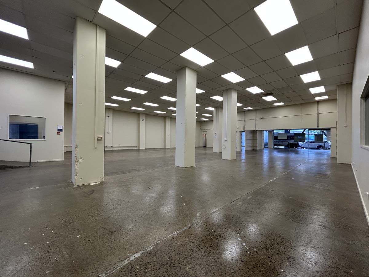 Spacious, empty retail or office space with high ceilings and bright lighting.