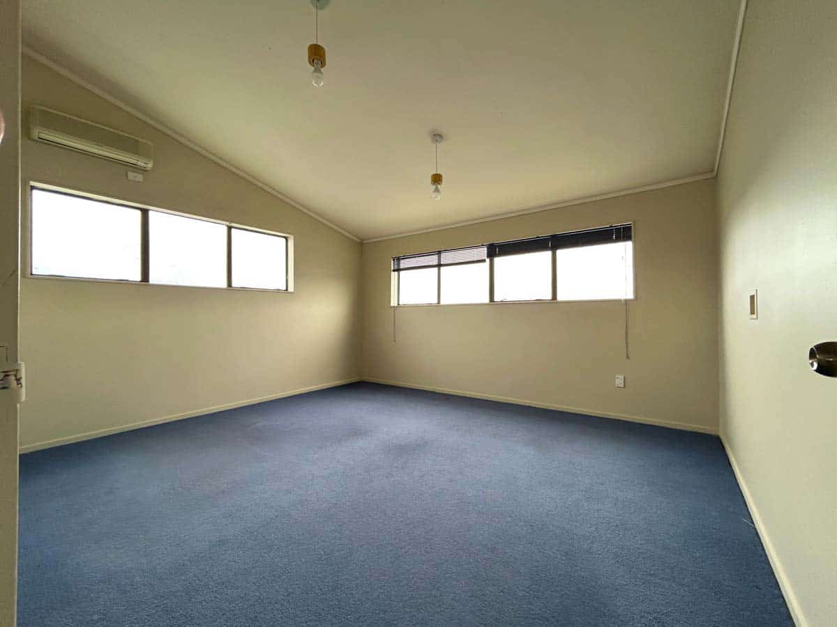 Interior room with large windows, neutral walls, and blue carpet flooring.