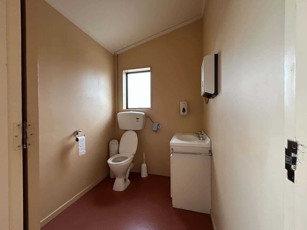 Small bathroom with toilet, sink, and window, designed for accessibility.
