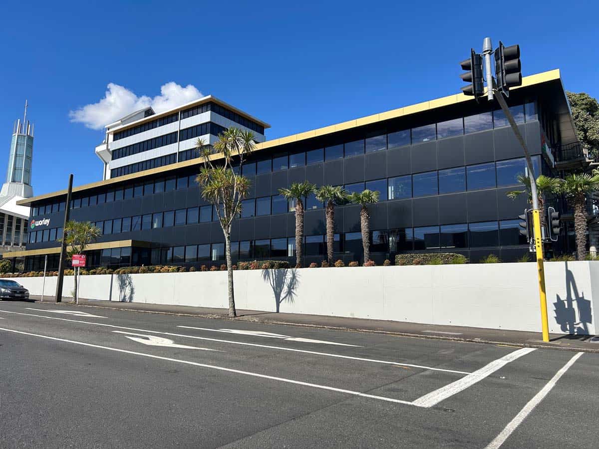 Contemporary black glass office building with palm trees in Auckland, NZ.