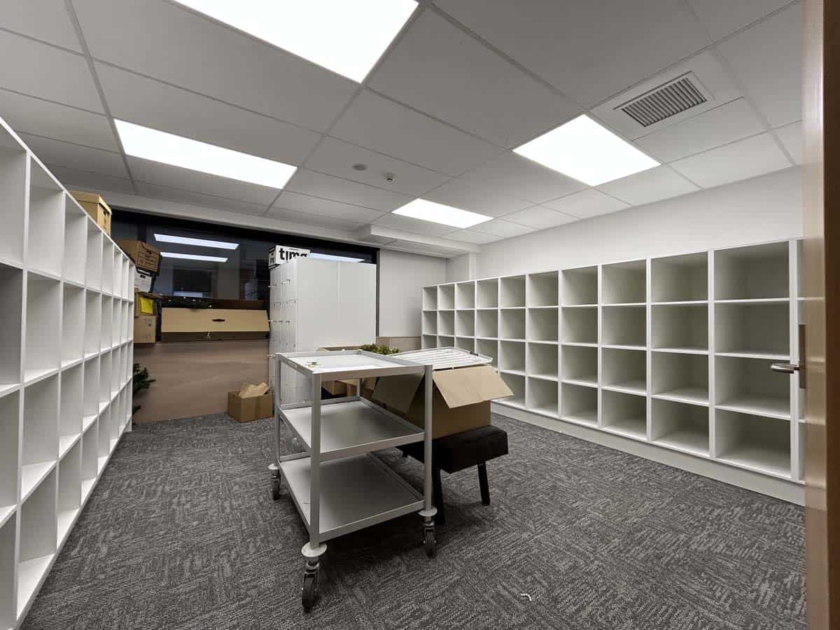 Modern office storage room with white shelving units and a central table.