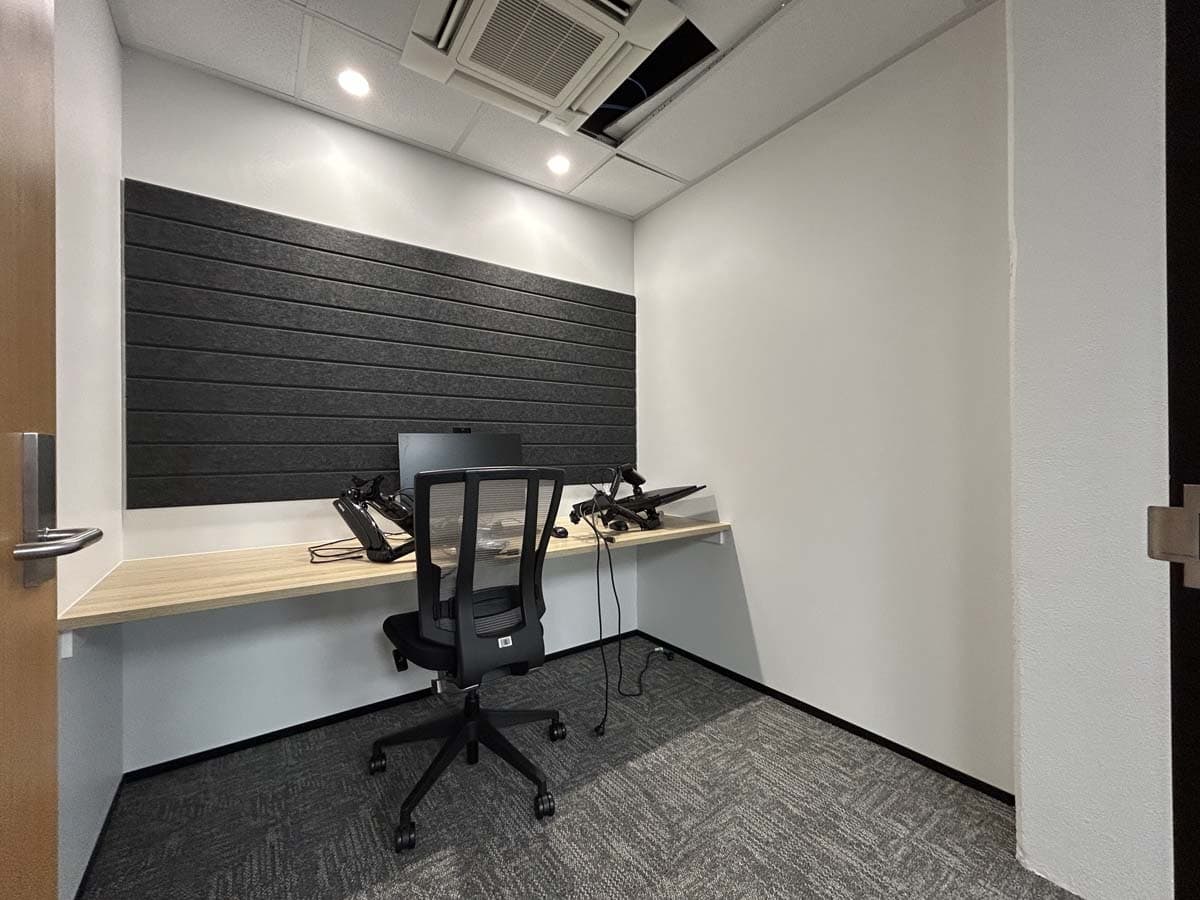 Modern office workspace with desk, chair, and acoustic wall panels.