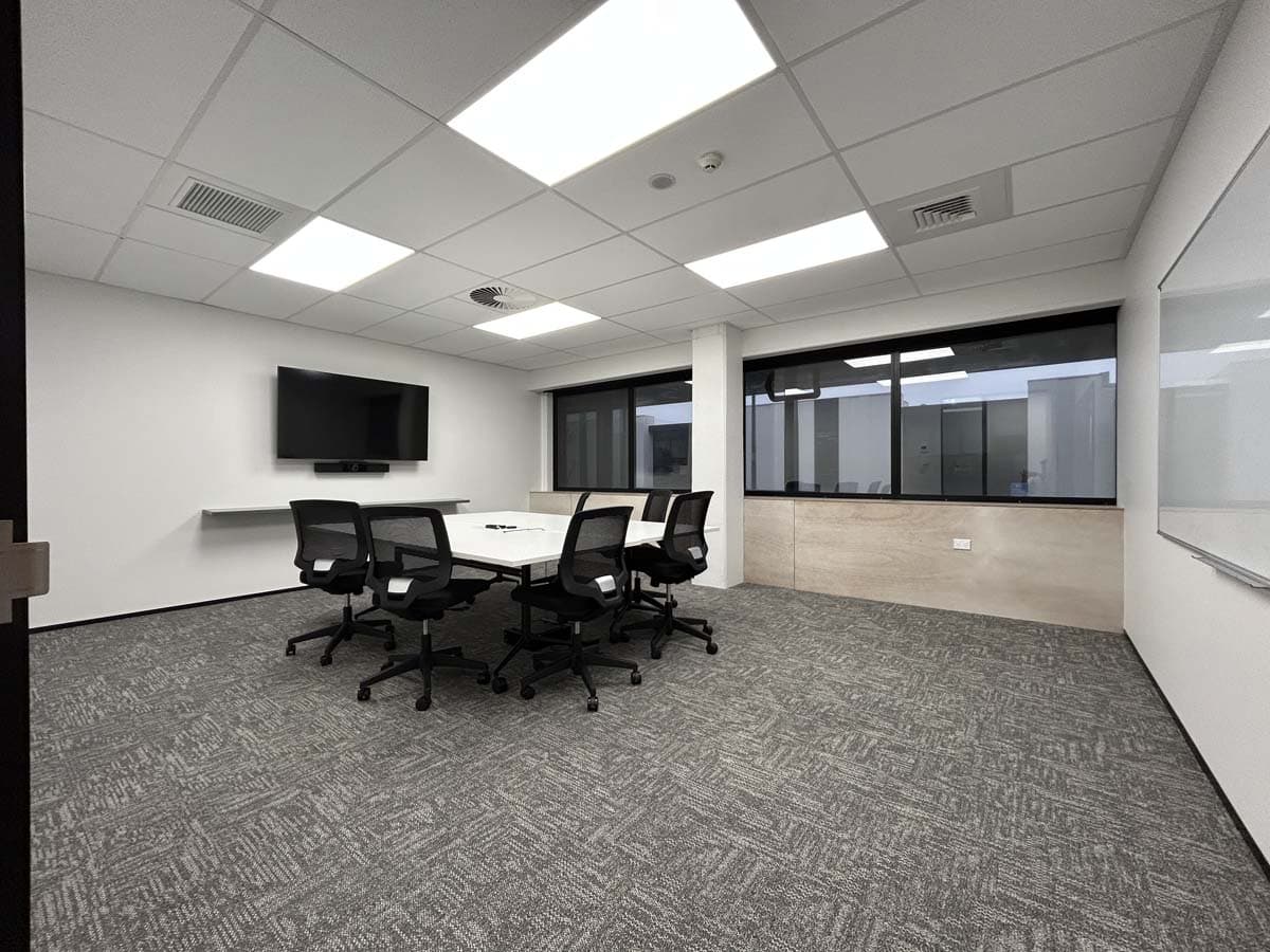 Conference room with white walls, large windows, and a mounted TV for meetings.