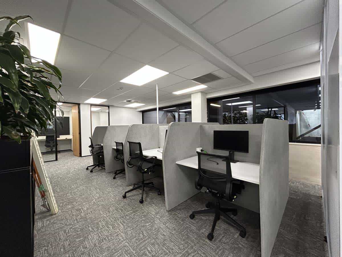 Modern office cubicles with computers and chairs.