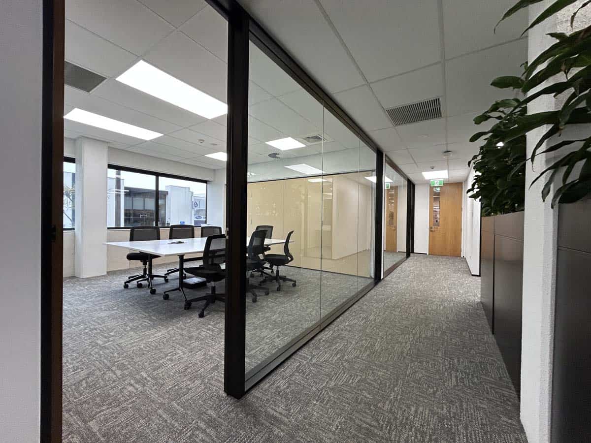 Office meeting room with glass walls, conference table, and ergonomic chairs.
