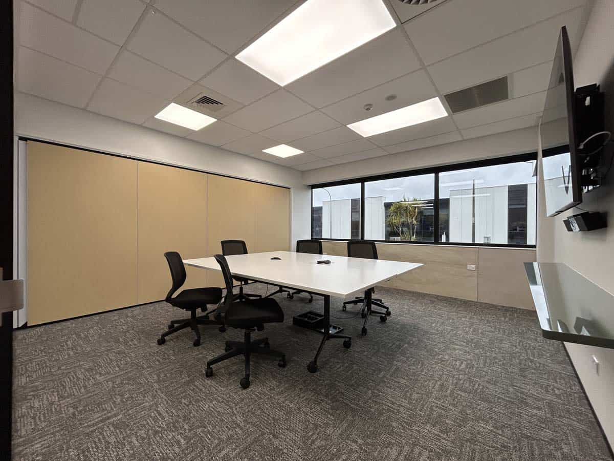 Conference room with large windows, meeting table, and office chairs.