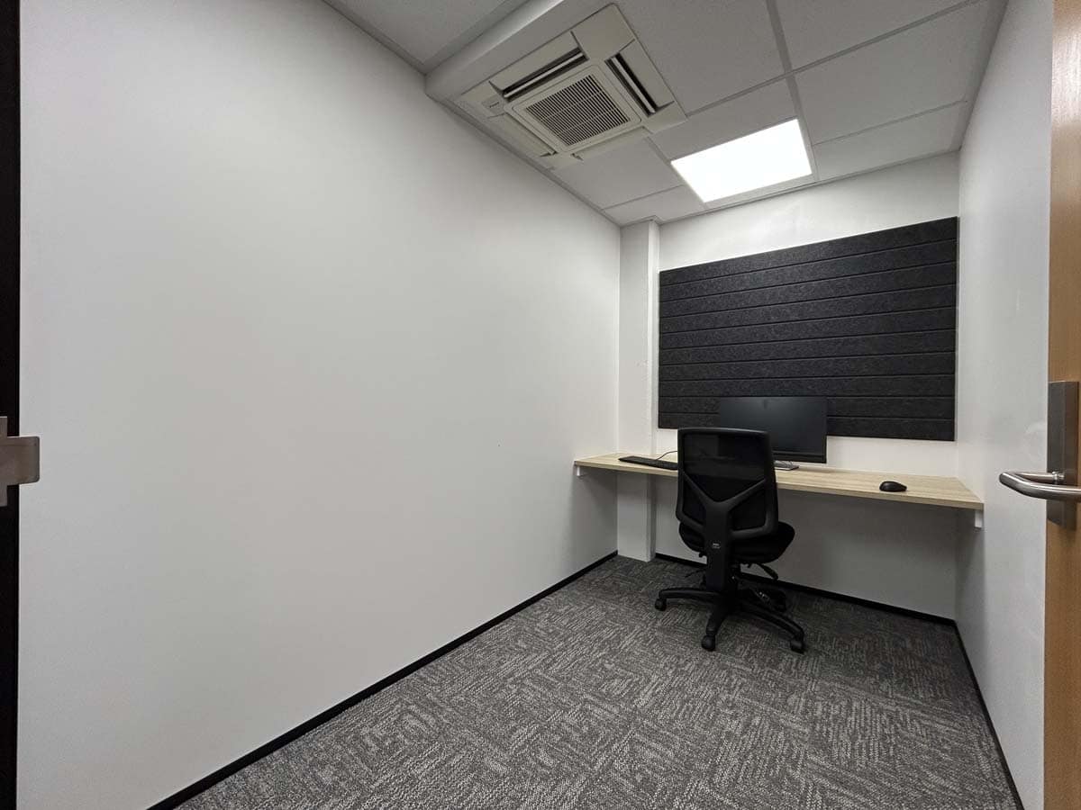 Compact office with desk, chair, and soundproof wall panel.