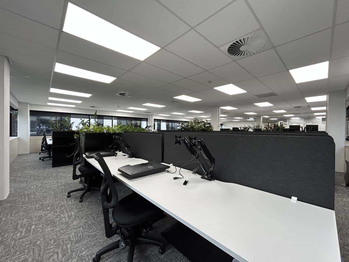 Modern open-plan office with desks and ergonomic chairs.