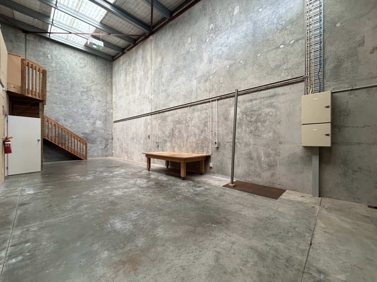 Spacious industrial warehouse with concrete floors, high ceiling, and utility pipes.