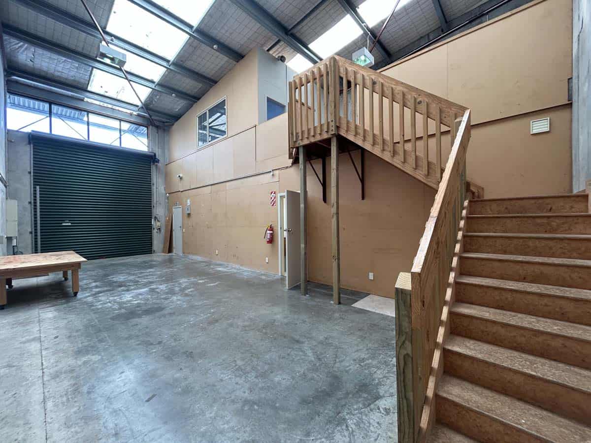 Industrial warehouse interior with wooden staircase and high ceiling.