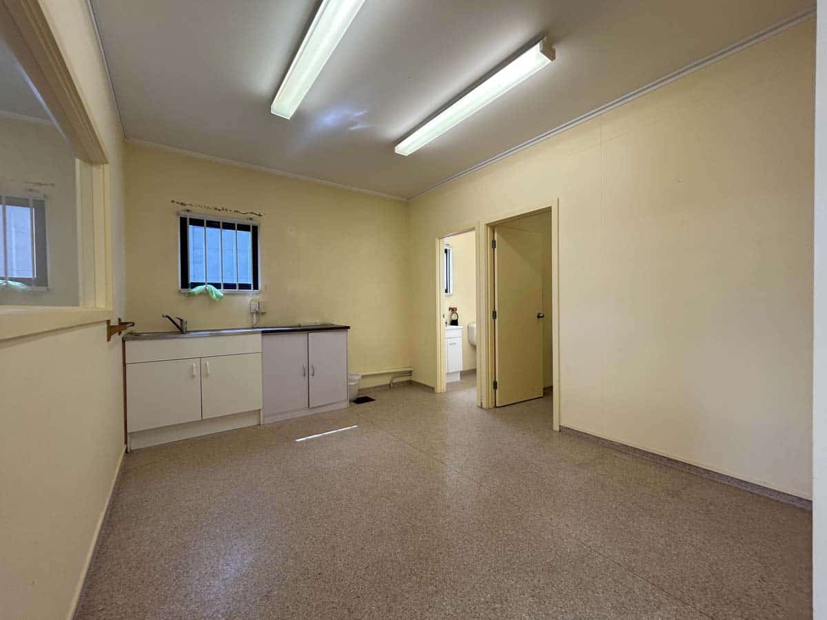 Office room with beige walls, ceiling lights, and a small window.