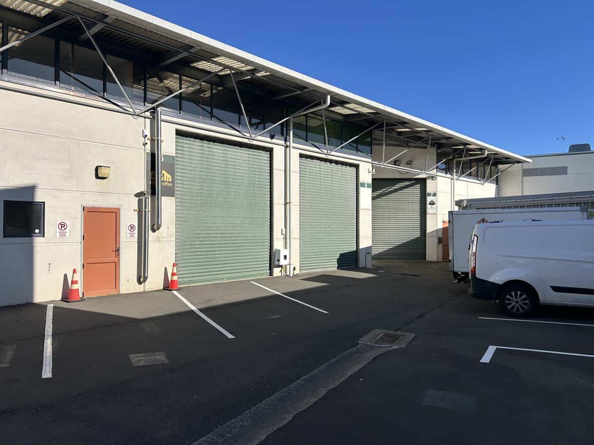 Modern warehouse with loading docks and parking area in an industrial setting.