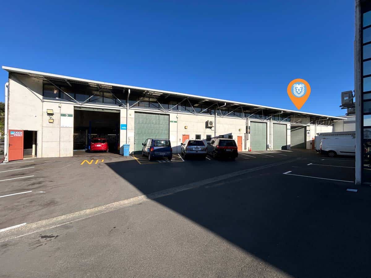 Modern warehouse with parking lot and distinctive roof design in Auckland.