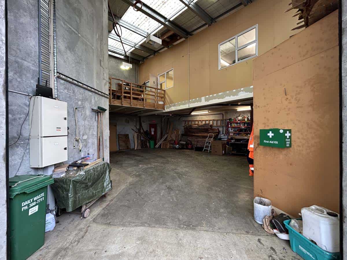 Industrial warehouse interior with storage shelves, equipment, and workspace.