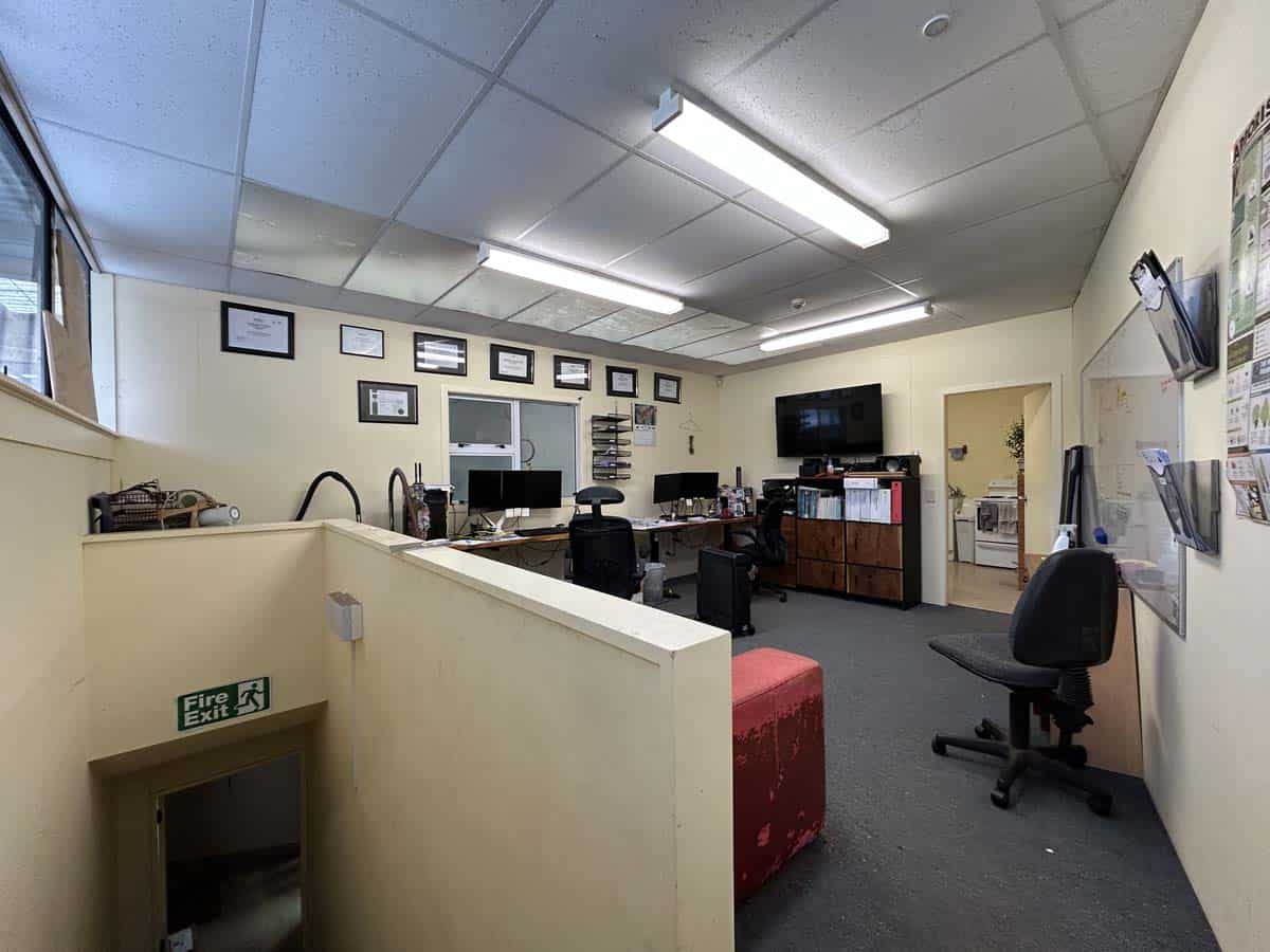 Interior view of a professional office space with desks, chairs, and wall-mounted certificates.