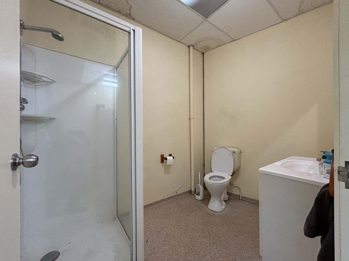 Simple bathroom with shower, toilet, and sink in a commercial space.