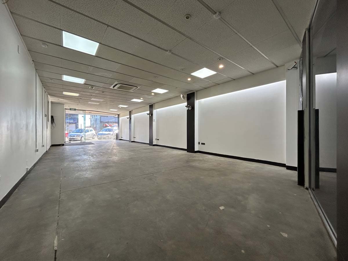 Empty commercial space with modern lighting and large glass windows.