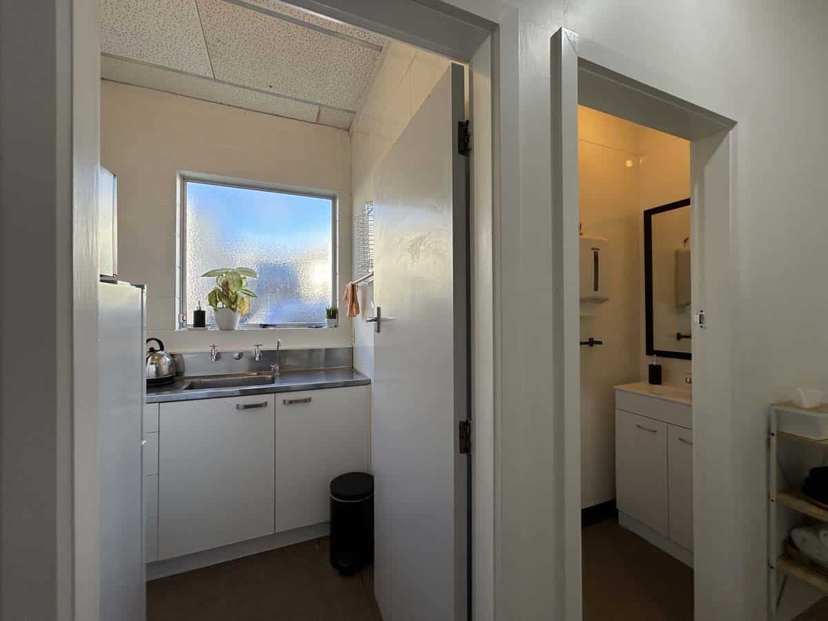 Modern office kitchen and bathroom with white cabinetry, natural light, and clean design.