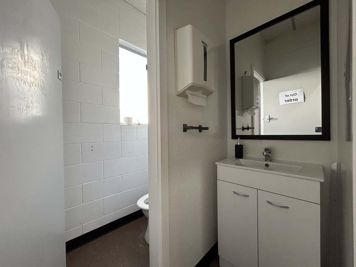 Modern bathroom with white vanity, mirror, and wall-mounted accessories.