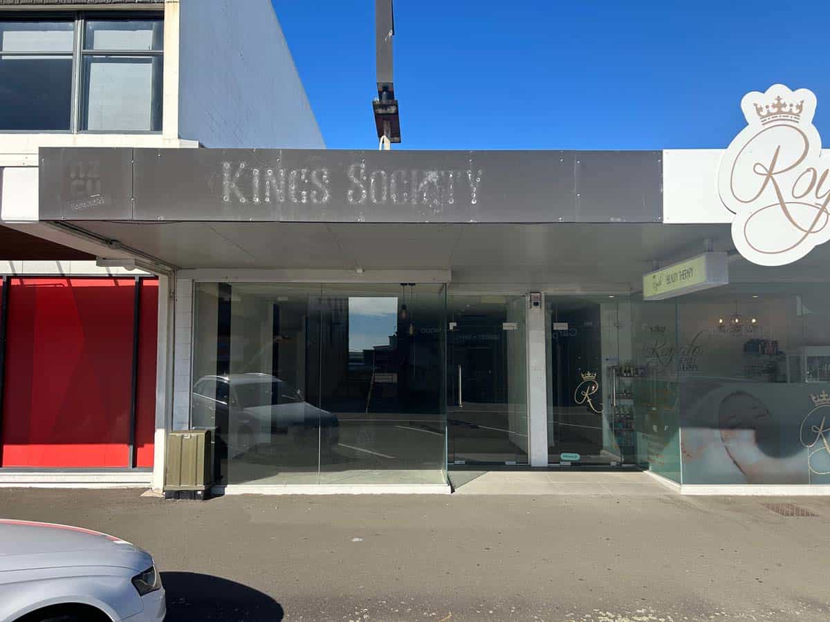 Modern storefront of Kings Society with glass doors and signage in a city setting.