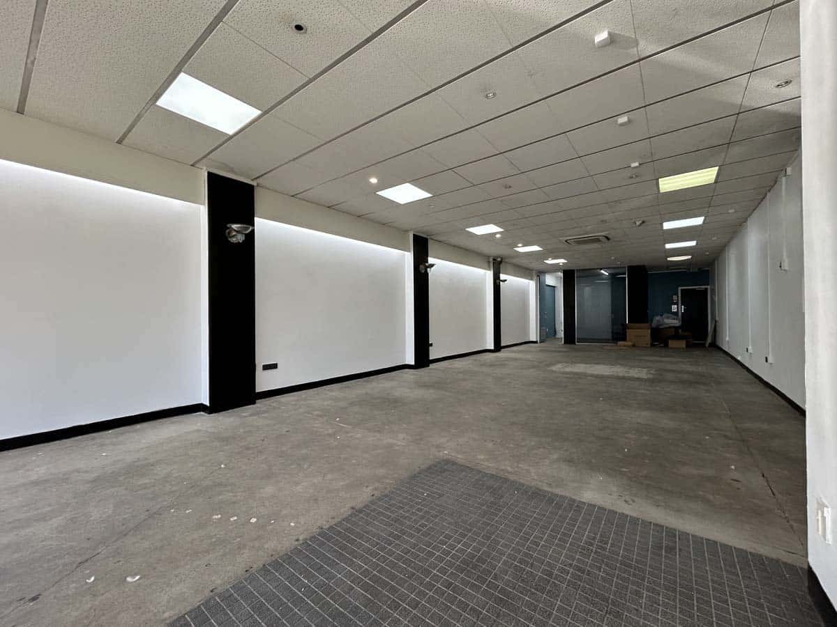Modern, empty commercial space with white walls and ceiling lighting.