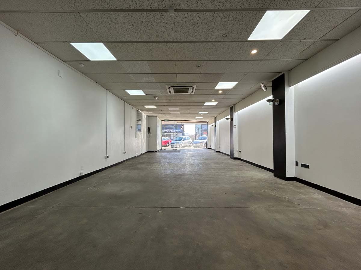 Empty commercial space with white walls and ceiling lighting.