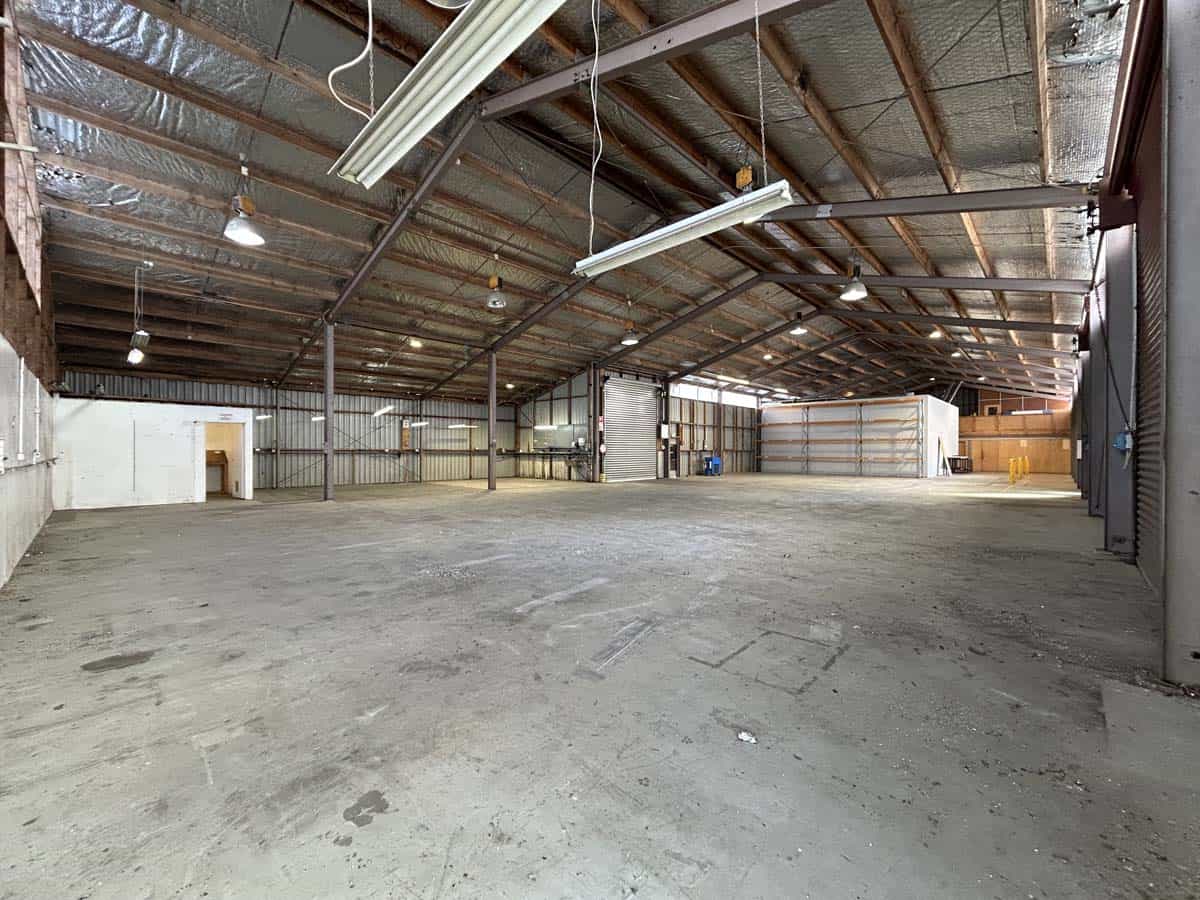 Warehouse interior with high ceilings and industrial lighting, empty space for storage or events.