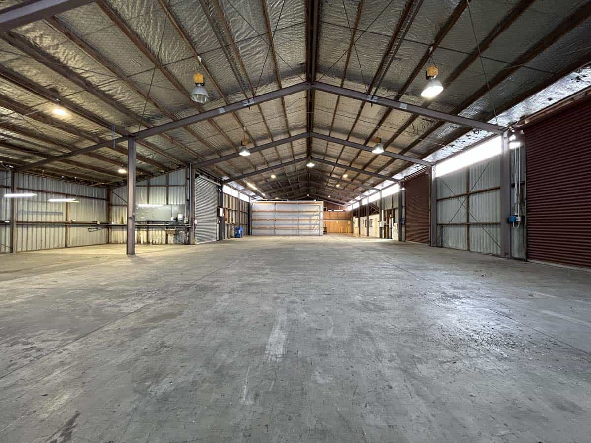 Empty industrial warehouse with high ceiling and metal framework.