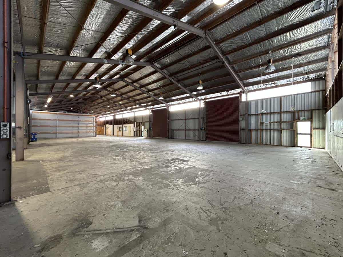 Empty industrial warehouse with high ceilings and metal framework.