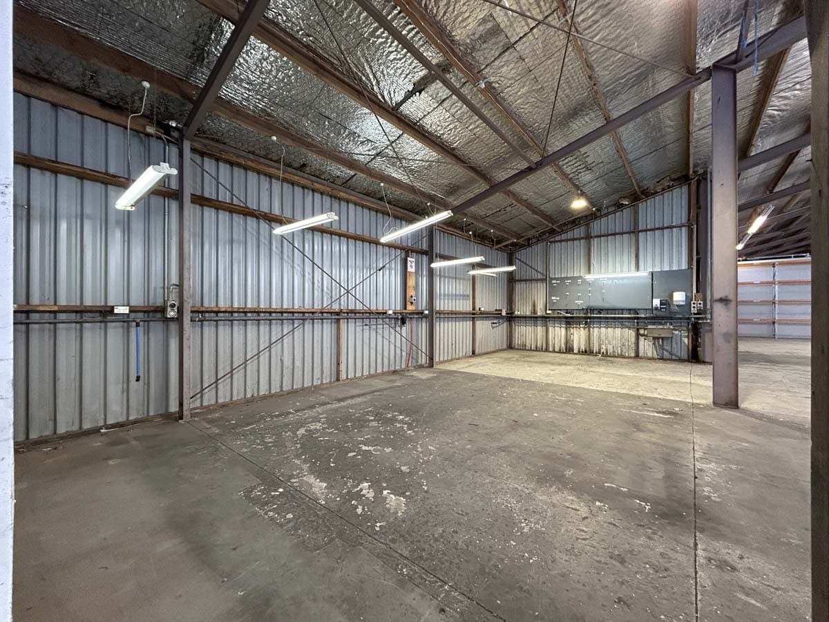 Spacious warehouse with metal walls and ceiling, industrial lighting, and concrete floor.