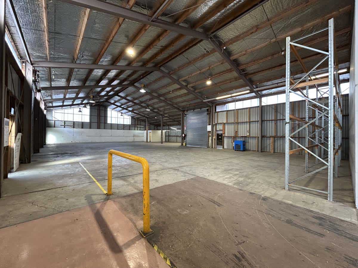 A spacious warehouse with high ceilings, scaffolding, and safety barriers for industrial use.
