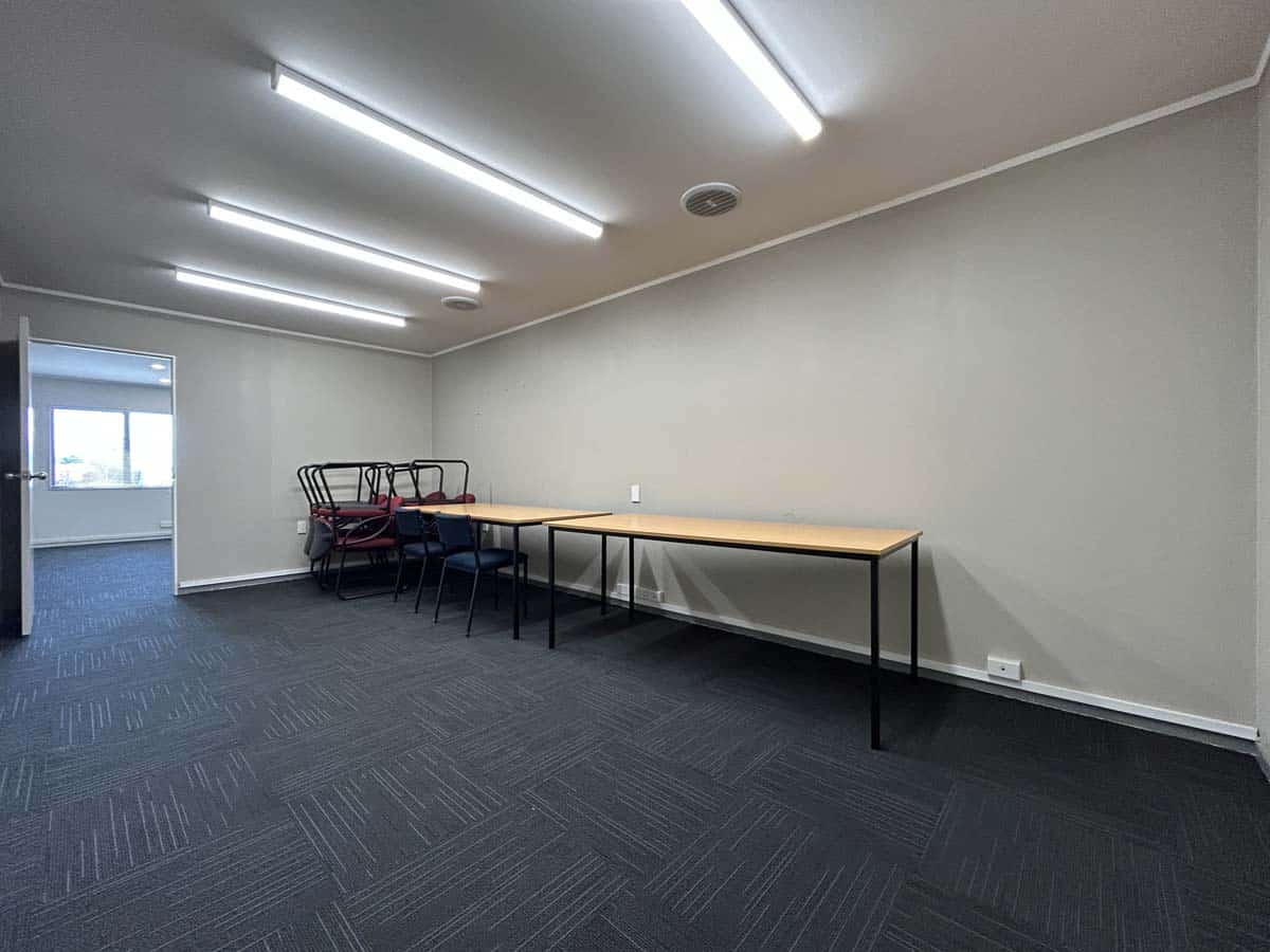 Modern, empty meeting room with tables, chairs, and ceiling lights.