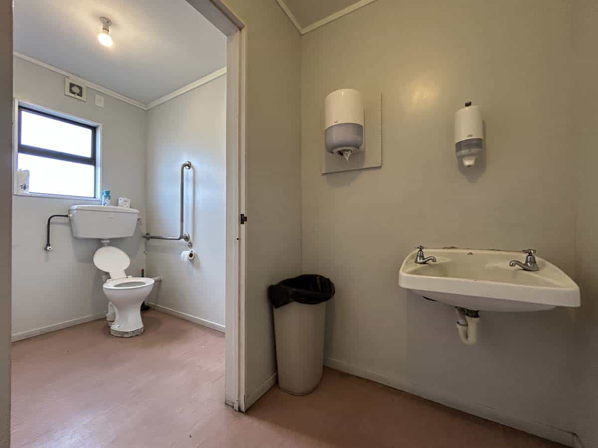 Accessible bathroom with toilet, sink, and hygiene supplies.