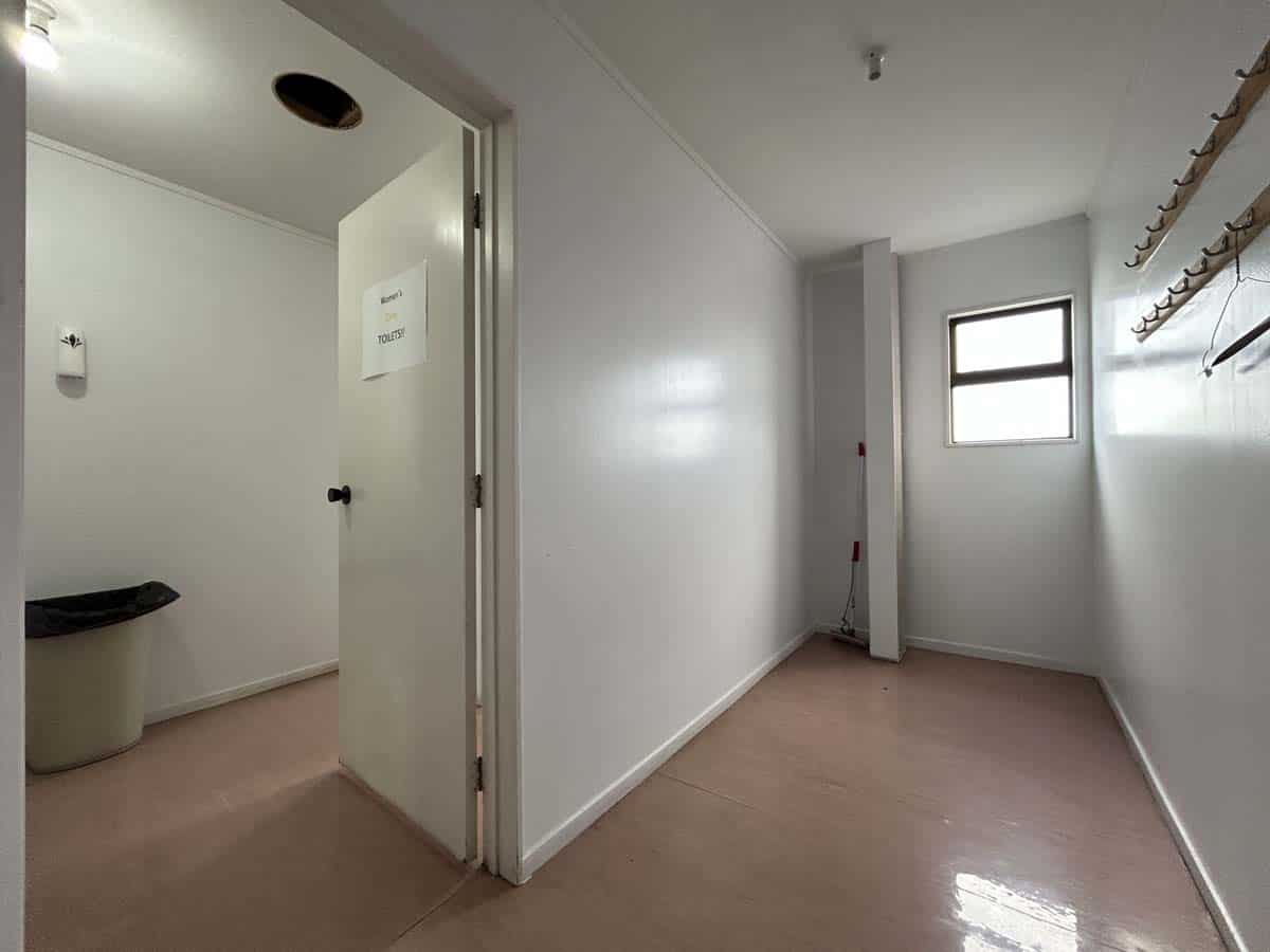 Empty room with white walls, wooden floor, and a window, featuring wall-mounted shelves.