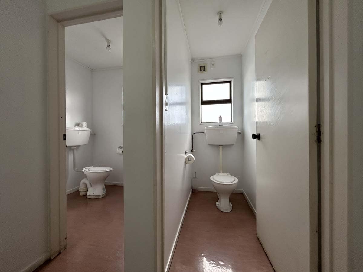 Small bathroom with white walls, toilet, and window in a residential home.