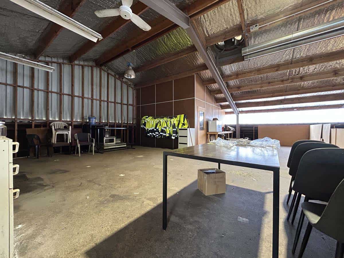 Spacious indoor event area with tables, chairs, and high-visibility safety vests.