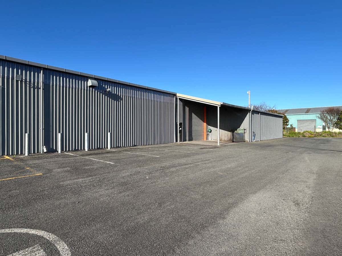 Modern industrial building with metal siding and spacious parking lot.