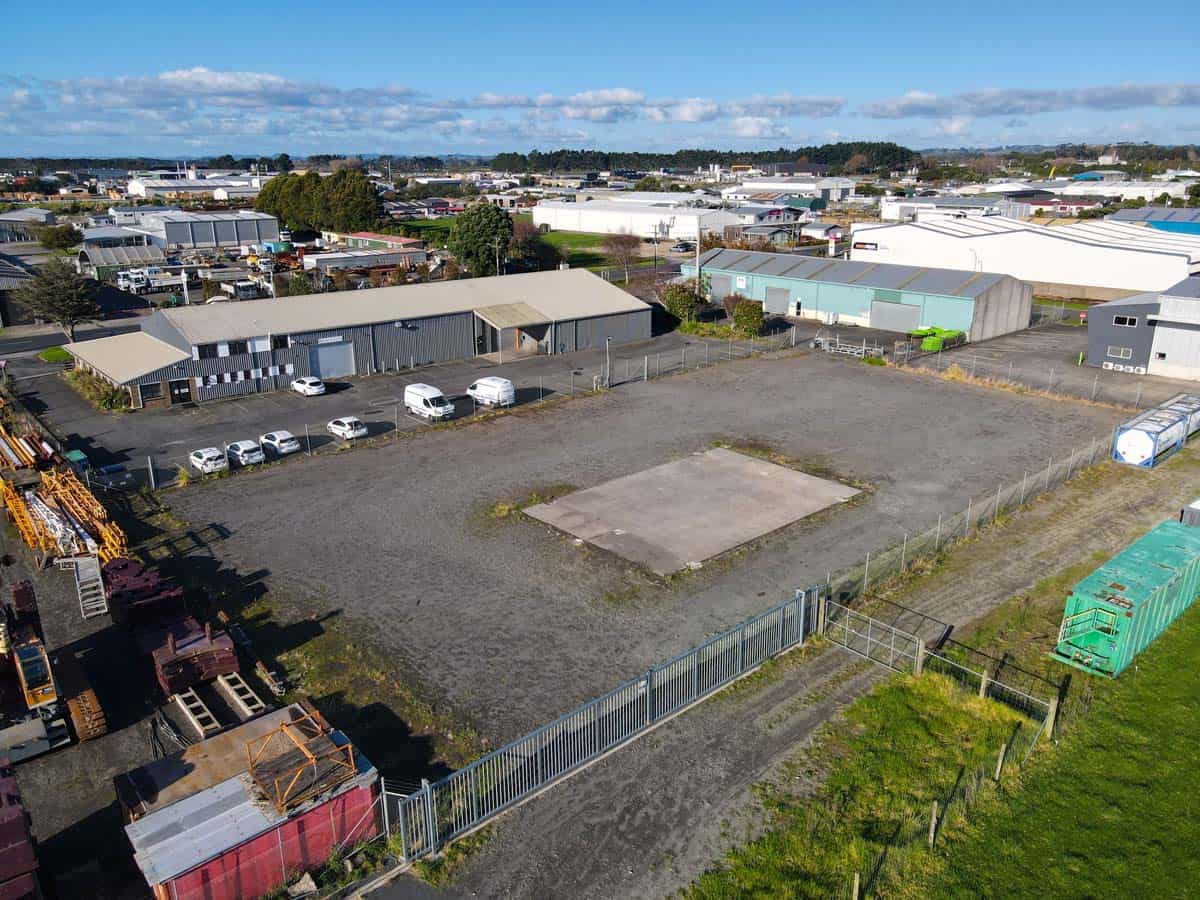 Industrial warehouse complex with empty lot and storage containers in New Zealand.