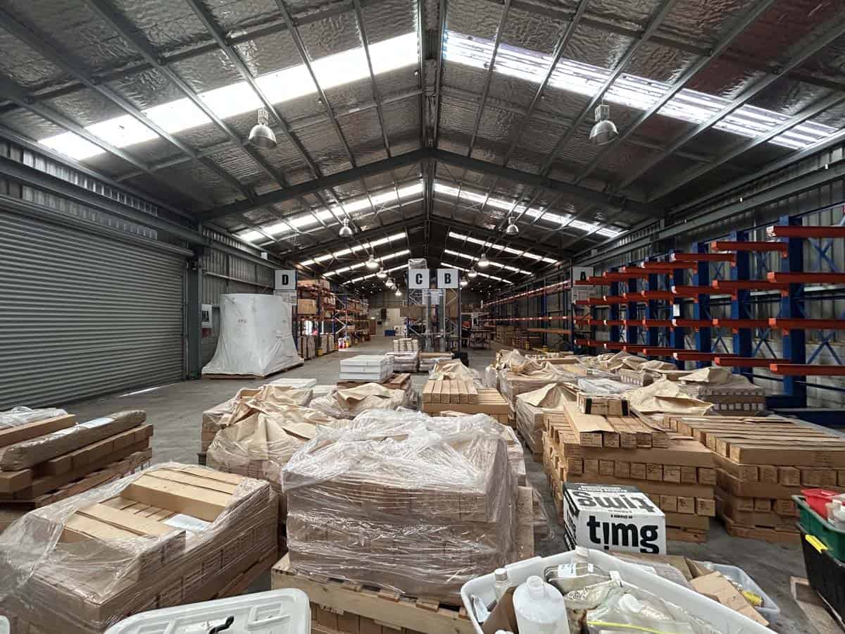 Industrial warehouse interior with stacked wooden pallets, packaging materials, and metal shelving.