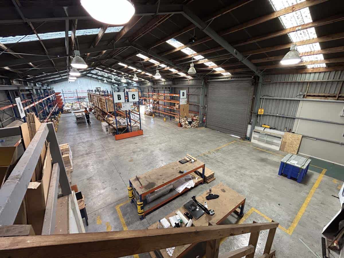 Bright industrial warehouse with shelving and workbenches.