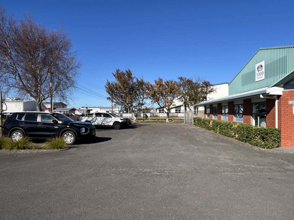 Exterior view of White Lion retail store with parking lot and trees in New Zealand.