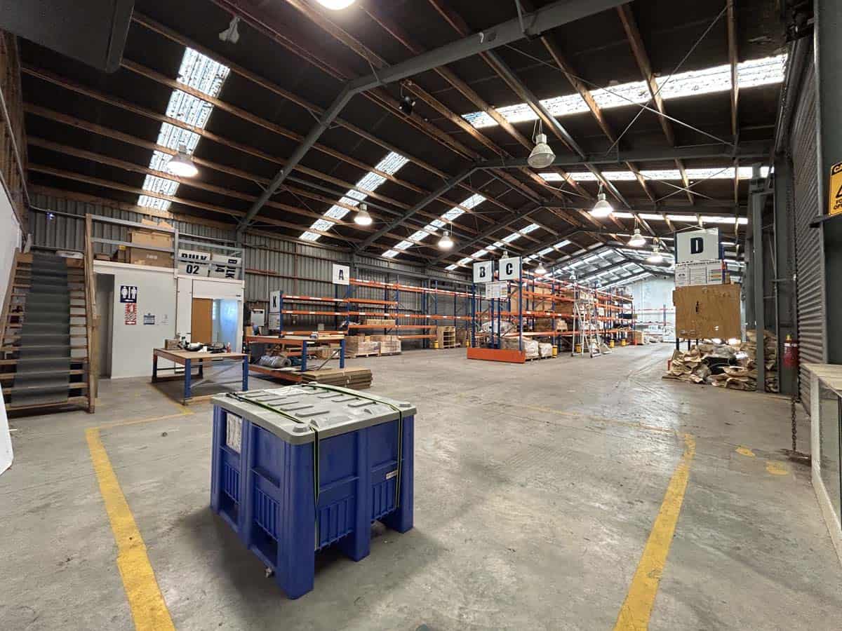Spacious warehouse interior with high ceilings, storage racks, and industrial lighting.
