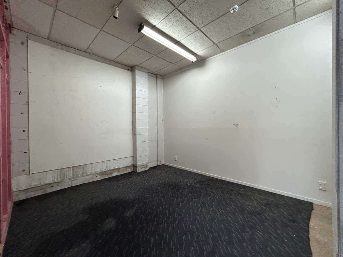 Empty office room with white walls and ceiling lighting.