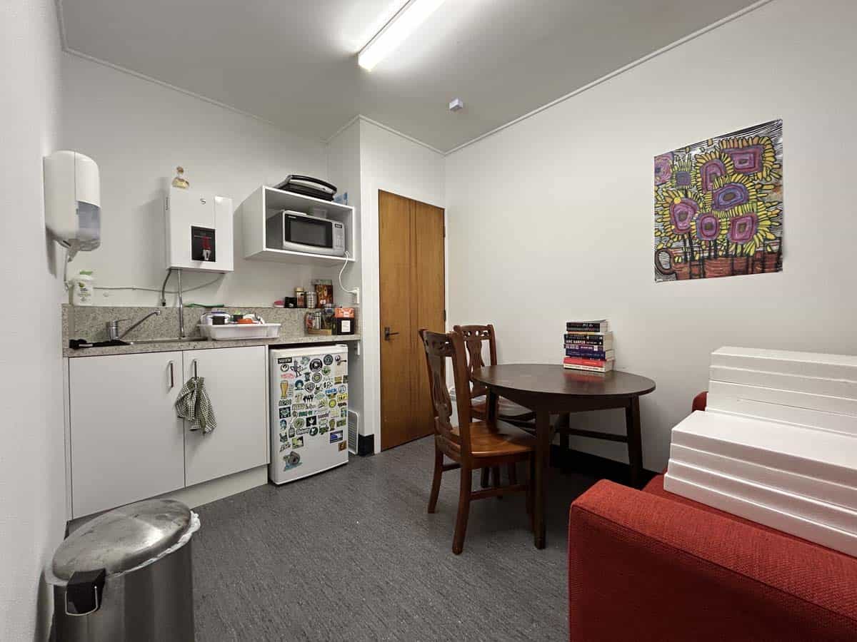 Modern office kitchen with dining table, chairs, and colorful artwork.