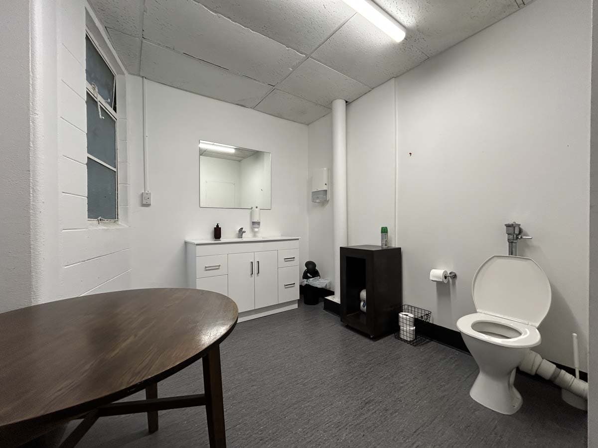 Simple office bathroom with toilet, sink, mirror, and minimal decor.