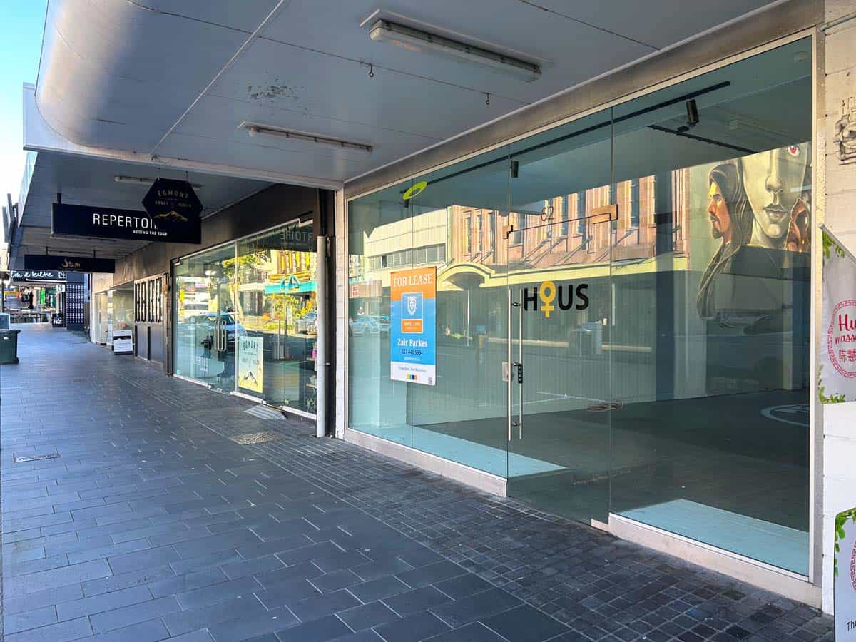 Modern commercial storefront with glass windows and signage in an urban setting.