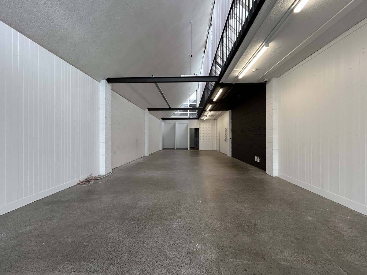 Empty commercial space with white walls and high ceiling.